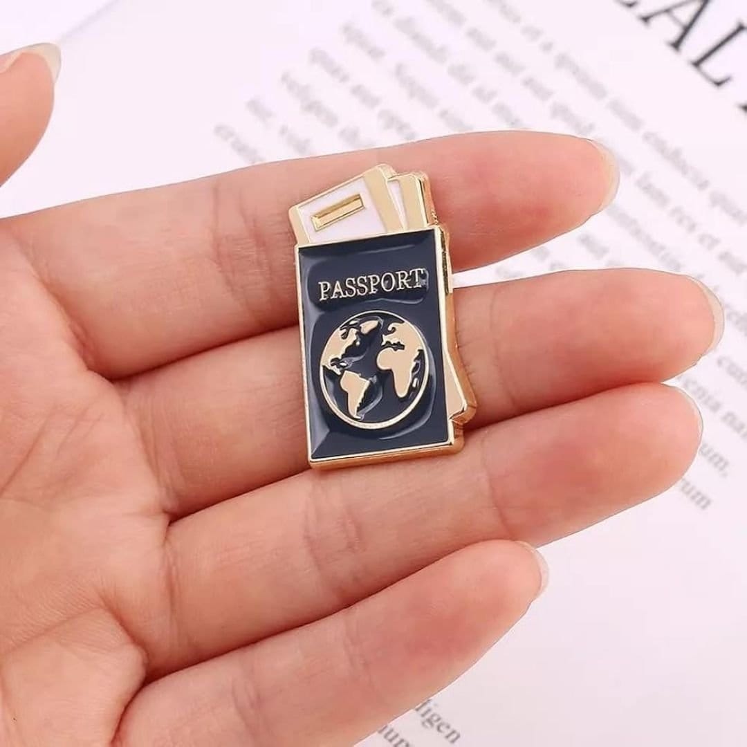 Passport enamel pin with navy cover gold globe and boarding pass cute travel lapel pin held in hand
