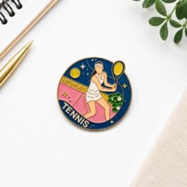 Tennis player enamel pin circular gold border navy pink court design on white background