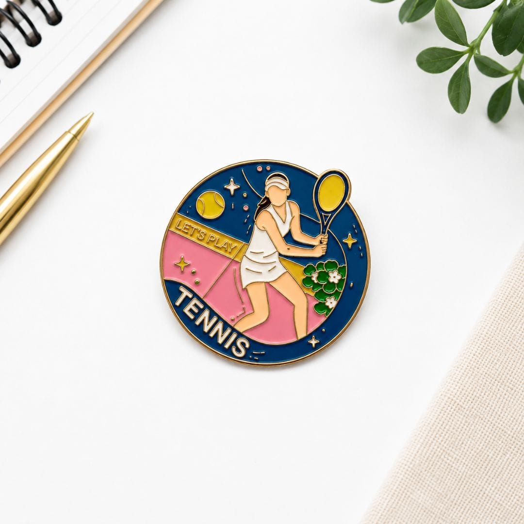 Tennis player enamel pin circular gold border navy pink court design on white background