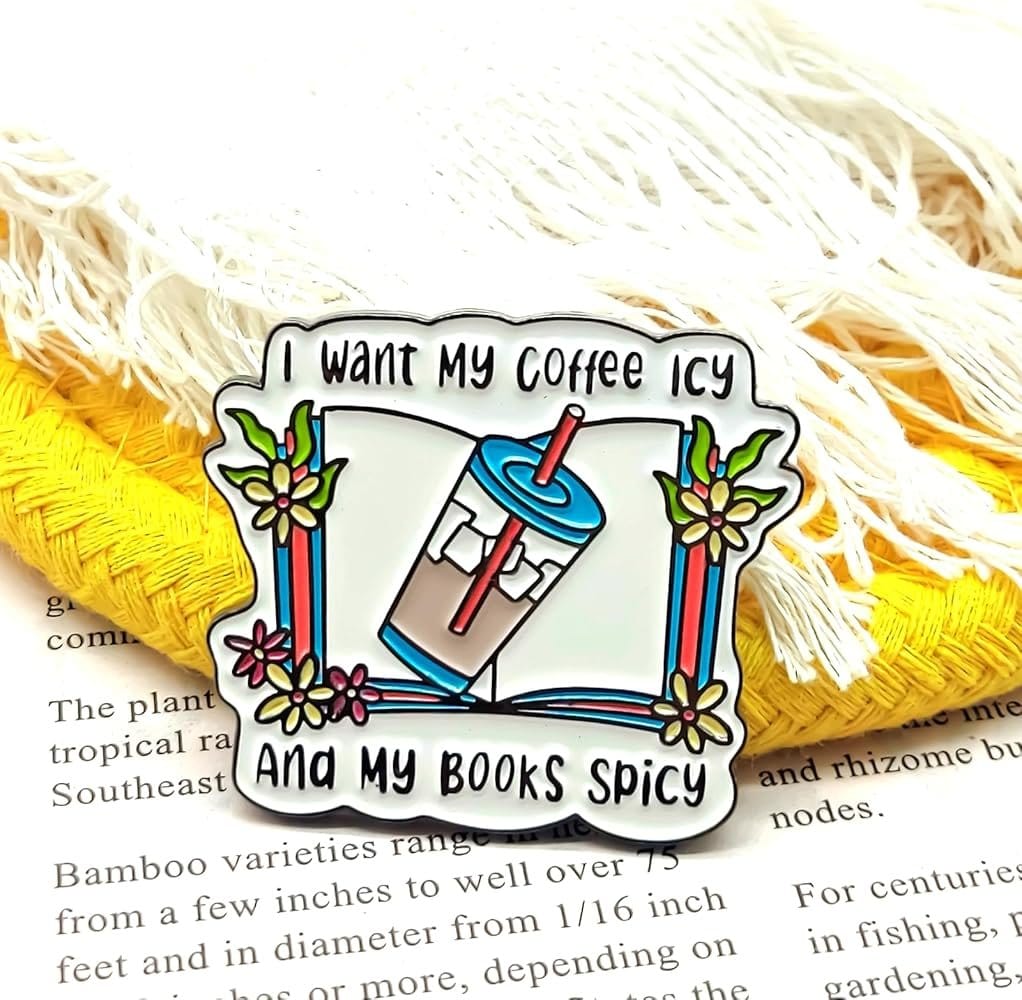 Metal lapel pin with white book and blue iced coffee illustration featuring the quote "I want my coffee icy and my books spicy"