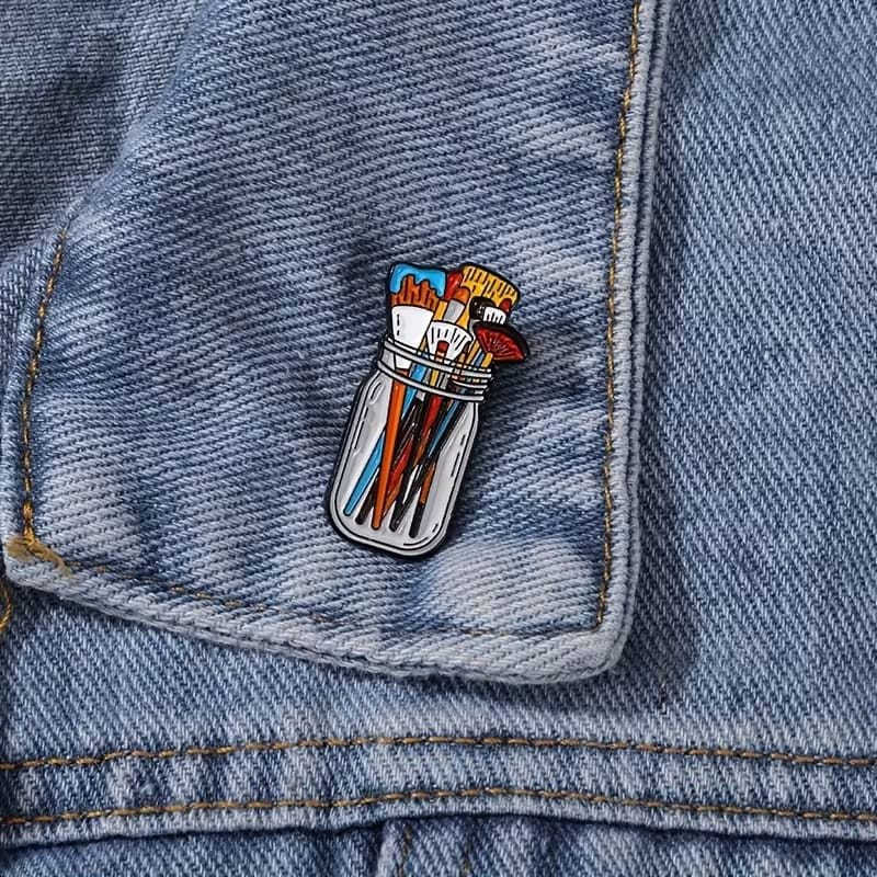 Paint brush jar artist enamel pin with colourful brushes in glass jar pinned on denim jacket