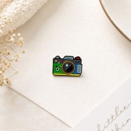 Retro camera enamel pin with colourful vintage camera design on white background