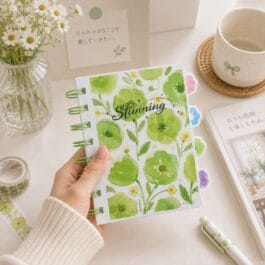 Open green floral spiral notebook showing ruled pages and colorful tabbed dividers