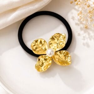 Gold tone flower hair tie with pearl center on black elastic